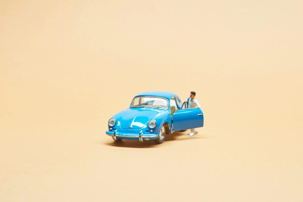 A detailed toy Volkswagen Beetle car with a miniature figure on a beige background.