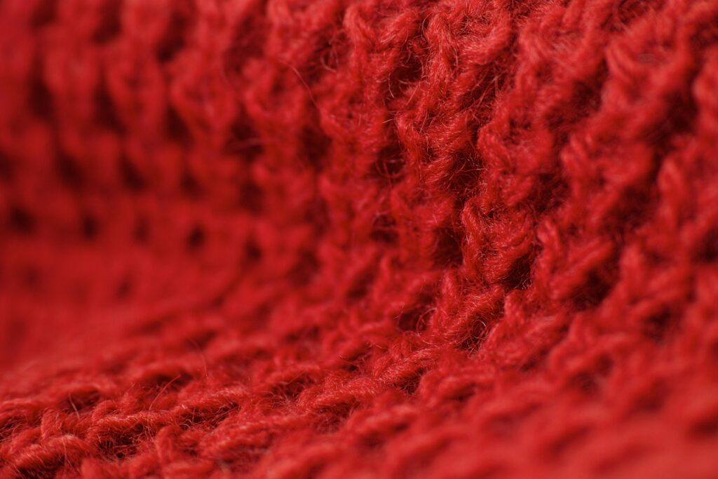 Detailed macro shot highlighting the texture of red woolen fabric, perfect for winter themes.