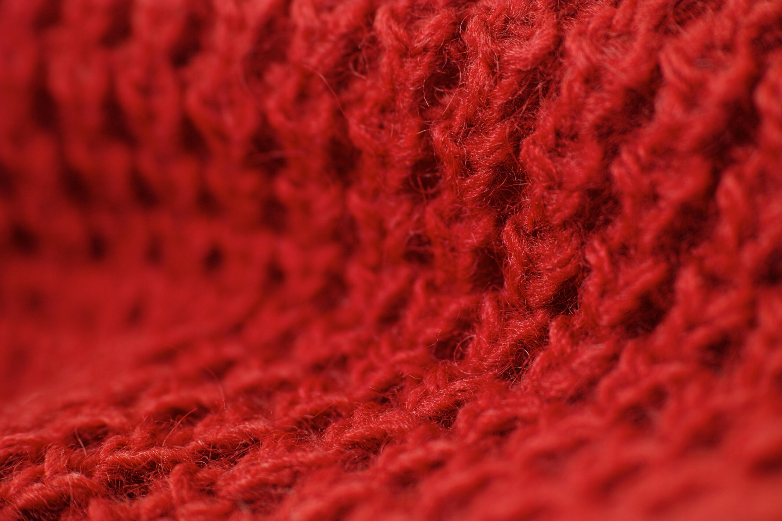 Detailed macro shot highlighting the texture of red woolen fabric, perfect for winter themes.
