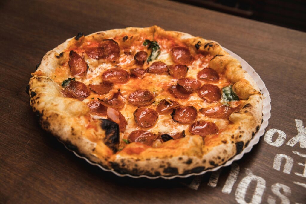 Close-up of a freshly baked pepperoni pizza with crispy crust on a wooden table.