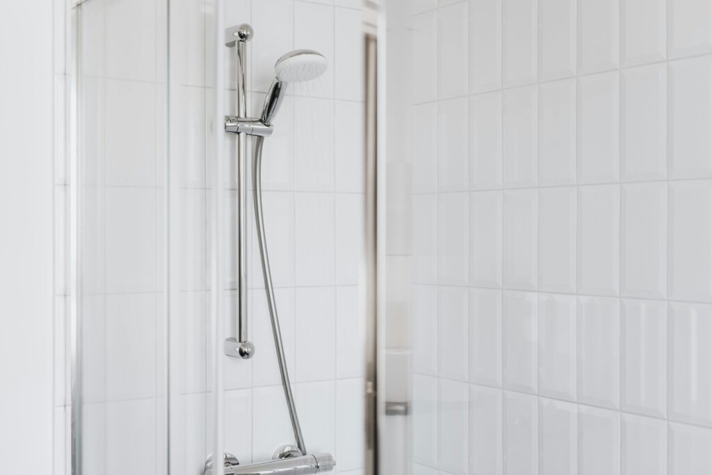 Stylish shower setup with chrome fixtures and clean white tiles.