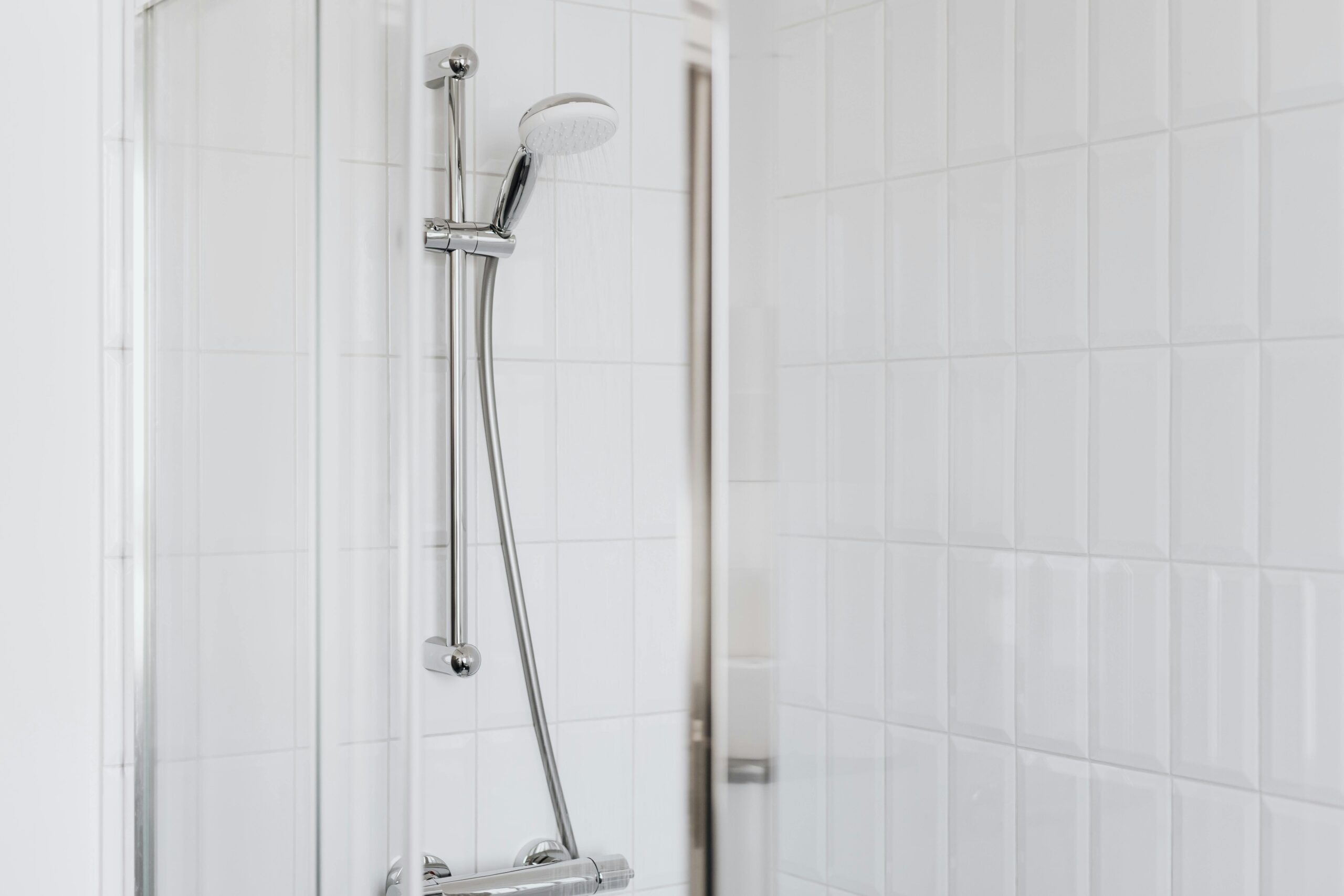 Stylish shower setup with chrome fixtures and clean white tiles.