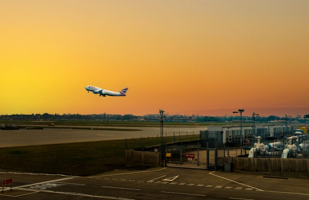 Airplane ascending during sunset at Heathrow Airport, capturing the vibrant sky.