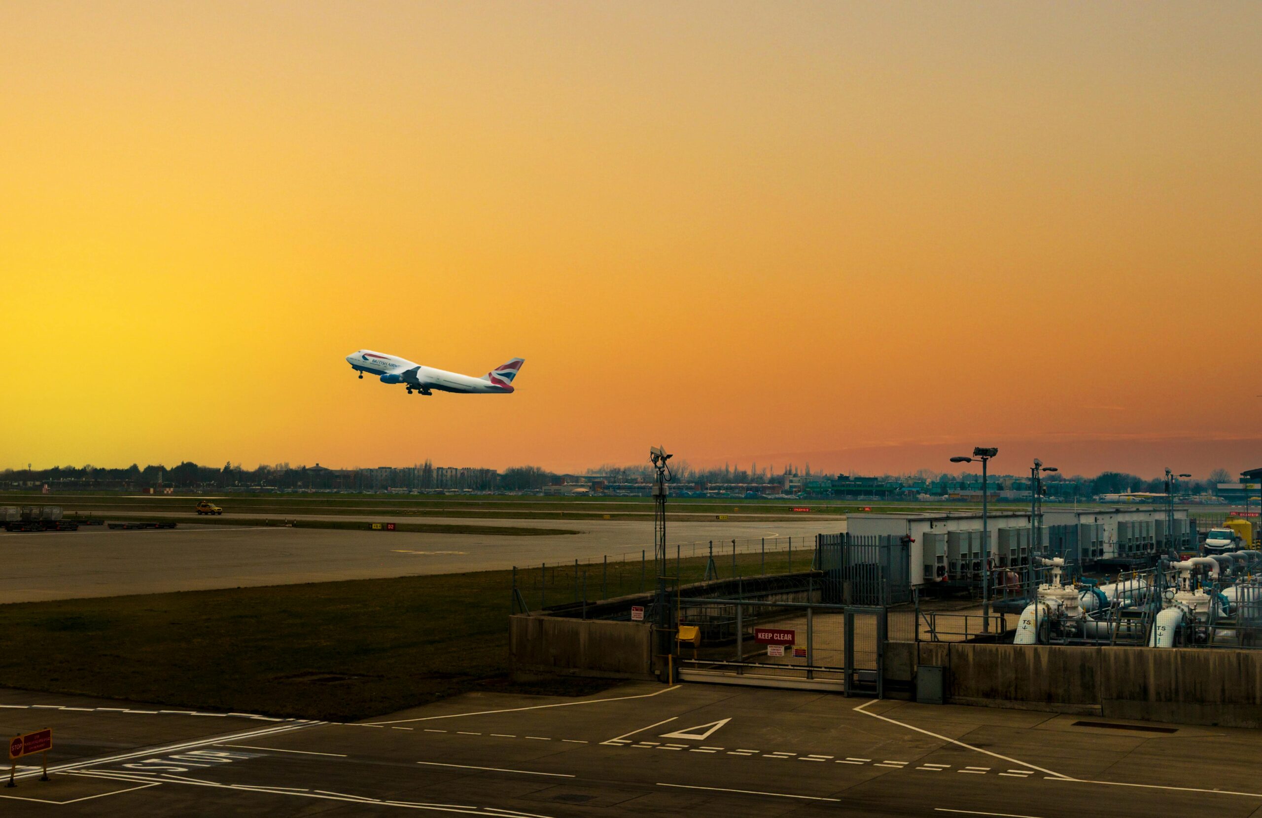 Airplane ascending during sunset at Heathrow Airport, capturing the vibrant sky.