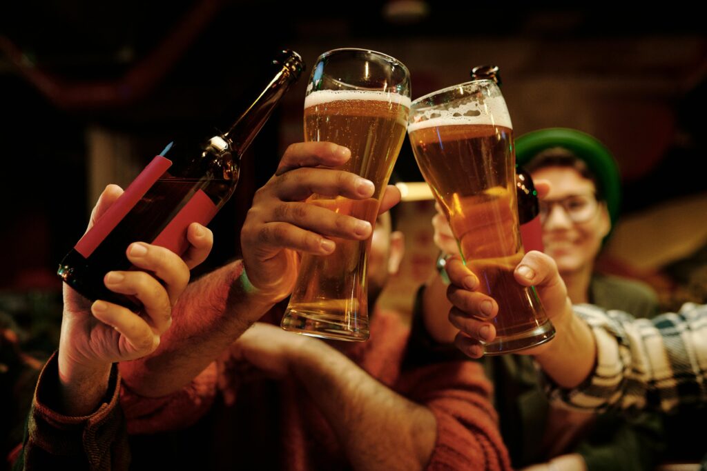 Cheerful group of friends toasting with beer glasses in a lively pub setting.