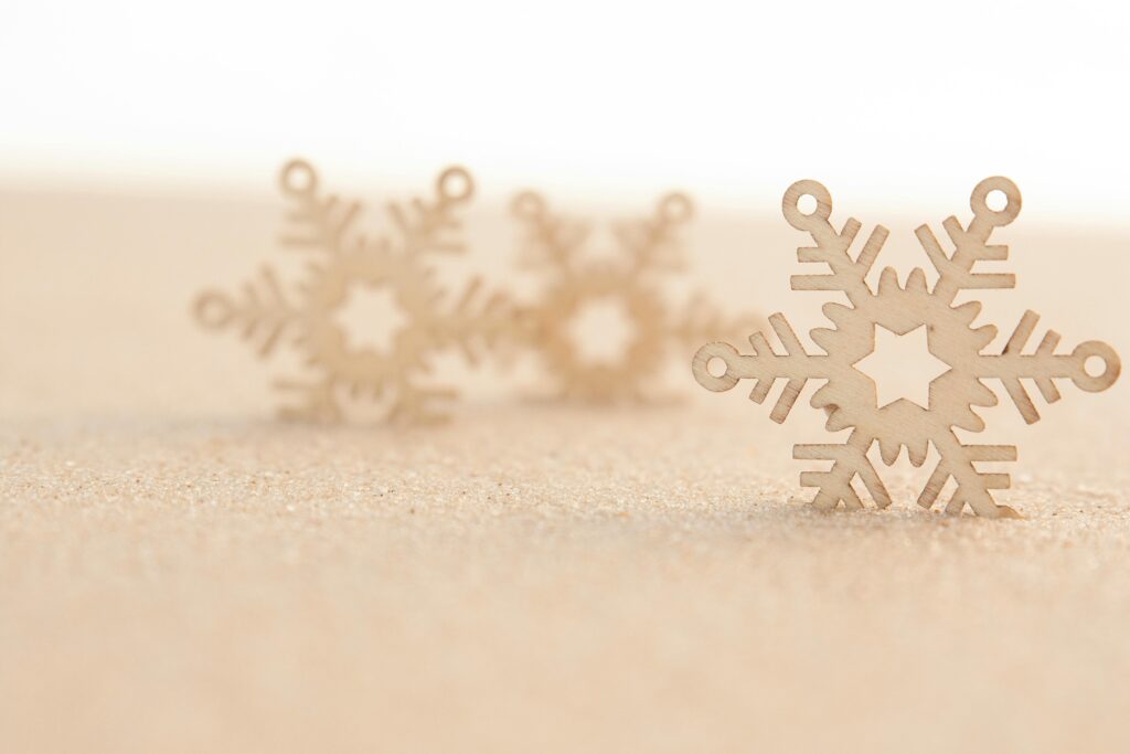Wooden snowflake decorations on a sandy surface, evoking a winter theme.
